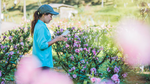 Side view of female researcher examining flowers on land