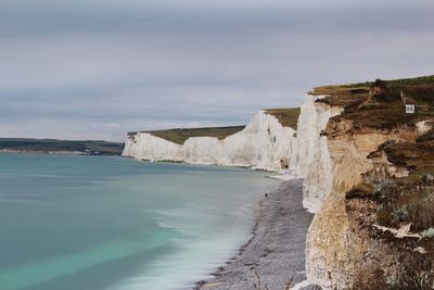 Scenic view of sea by cliff against sky