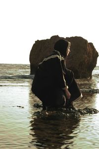 Woman standing on beach against clear sky