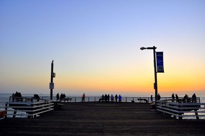 Silhouette pier on sea against clear sky during sunset