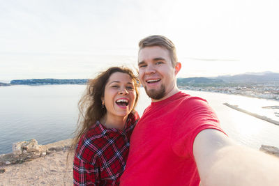 Portrait of smiling young couple at sea shore