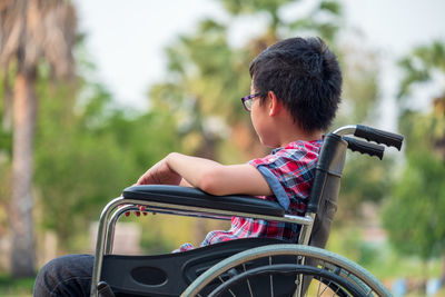 In the park, a child in a wheelchair. take a closer look at his steering wheel.