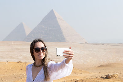 Young woman using mobile phone while standing at beach