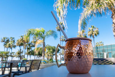 Fresh moscow mule cocktail with ice, lime and mint leaves in copper mug on swimming pool. 