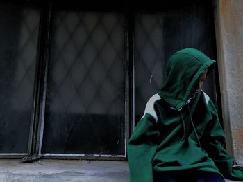 Man wearing hood while standing wall