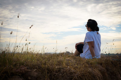 Full length of man sitting on field against sky
