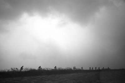 Silhouette people on field against sky
