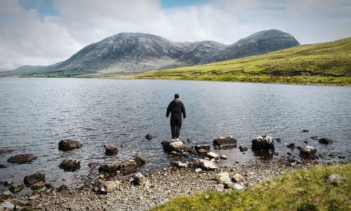 Landscape scenery, man on the rock at lough inagh, mountains at connemara, galway, ireland