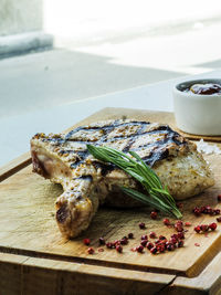 Close-up of fresh grilled beef steak on wooden cutting board with spices