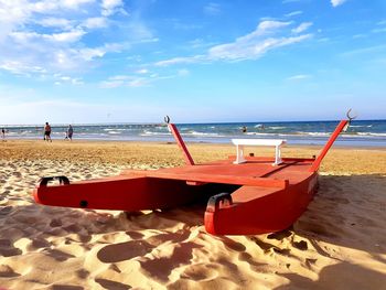 Deck chairs on beach against sky