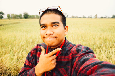 Portrait of young man standing on grassy field