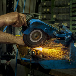 Cropped hands of man using circular saw on metal