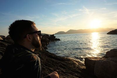 Man looking at sea against sky during sunset