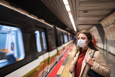 Woman wearing mask standing on railroad station platform