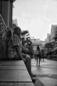 Children sitting in city against sky