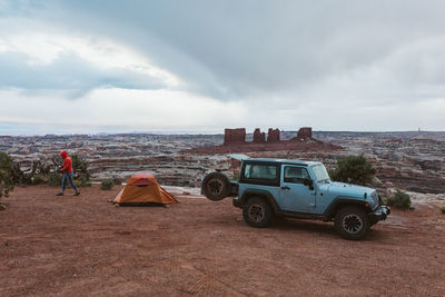 Jeep parked next to an orange tent on a rainy day in canyonlands utah