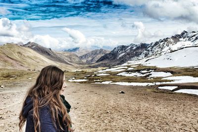 Woman standing on snowcapped mountain against sky