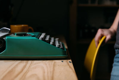 Green tipewriter in wood table with yellow chair and woman hands