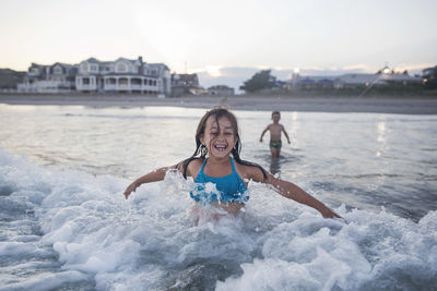 Portrait of happy friends at beach against sky