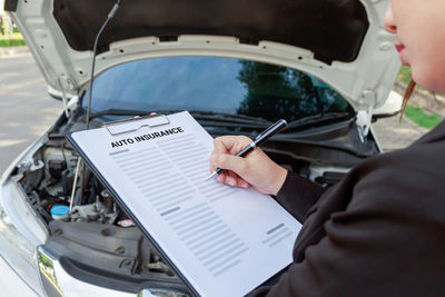 Midsection of woman holding insurance papers