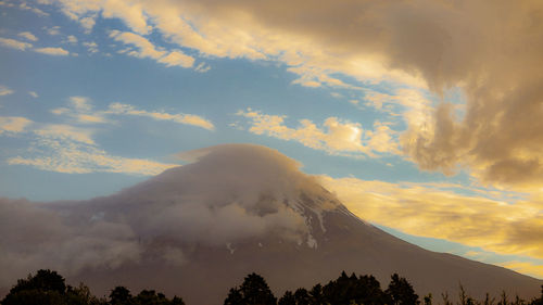 Low angle view of volcanic mountain against sky during sunset