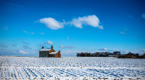 Building on snow covered land against blue sky, near ormskirk.