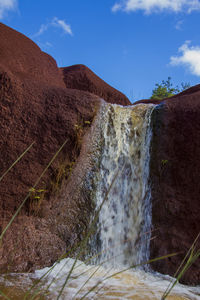 A small waterfall with a bright blue sky in the background. photographed in waimea canyon state park