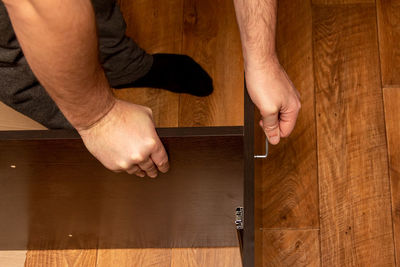 Midsection of man holding hands on hardwood floor