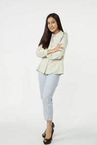 Portrait of smiling young woman standing against white background