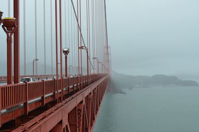 Suspension bridge over sea against sky