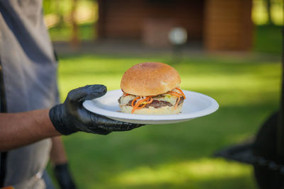 Midsection of man holding burger in plate