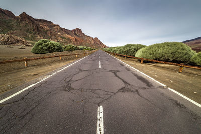 Road leading towards mountain against sky