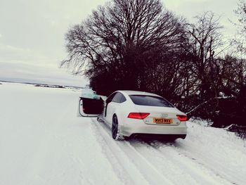 Snow covered car on road against sky