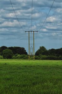 Electricity pylon on field against sky