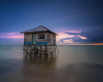 House amidst sea and building against sky