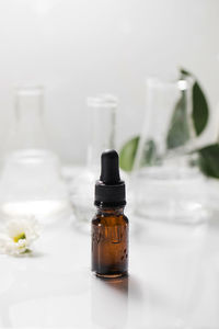 Glass dropper bottle with essential oil on wet table under falling down drops