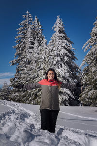 Portrait of woman standing on snow against trees