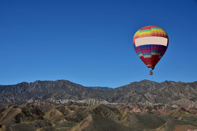 Hot air balloon flying over mountain against blue sky, zhangye danxia national geological park