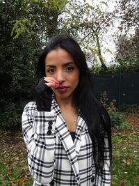 Portrait of young woman standing against plants