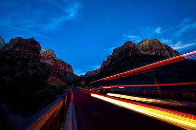 Light trails on road against sky at night