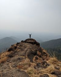 Rear view of man standing on mountain against sky