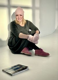 Portrait of smiling woman sitting on wall