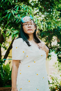 Portrait of a beautiful young woman standing against plants