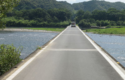 Empty road along trees and river