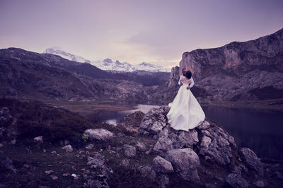 Woman with umbrella standing on mountain against sky