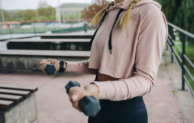 Midsection of woman exercising with dumbbell