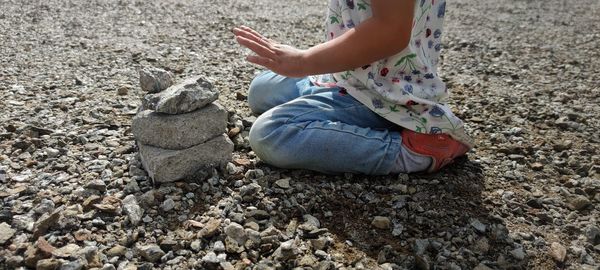 Low section of boy sitting on pebbles at beach