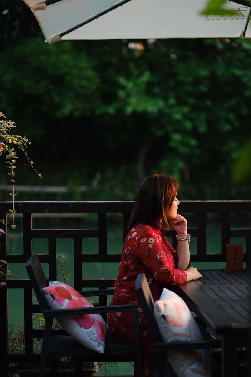 WOMAN USING PHONE WHILE SITTING ON BENCH