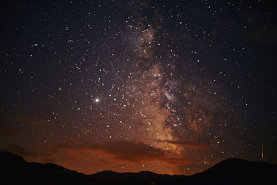 Silhouette mountains against star field at night