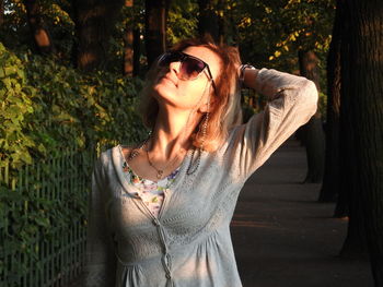 Beautiful young woman standing against trees